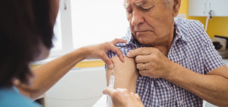 Female doctor giving an injection to an elderly man